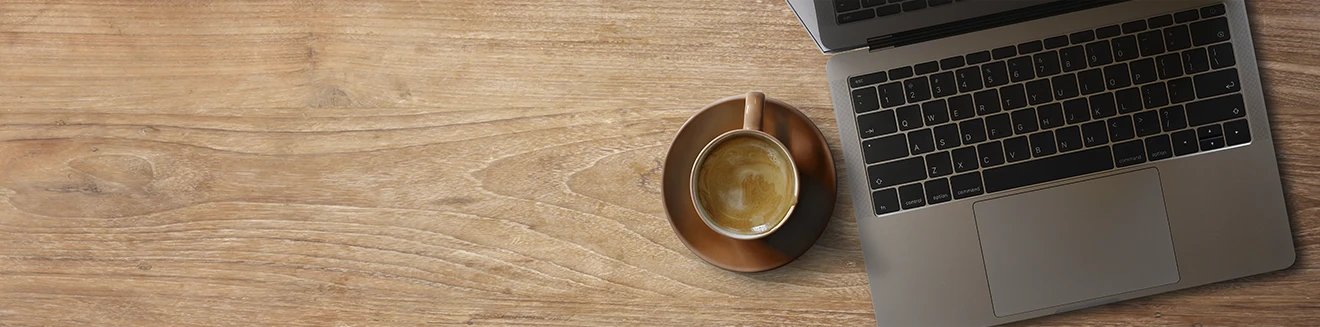 Mesa de trabalho com notebook e xícara de café